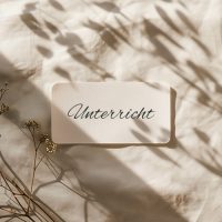 Karte mit der Aufschrift „Unterricht“ auf hellem Stoff mit sanften Schatten.