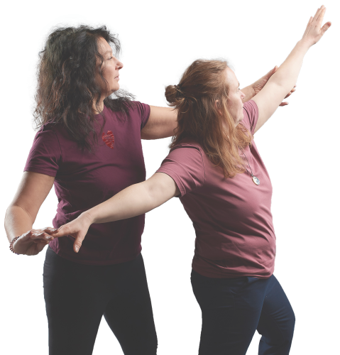 Zwei Frauen machen eine begleitete Yoga-Übung mit sanfter Unterstützung.